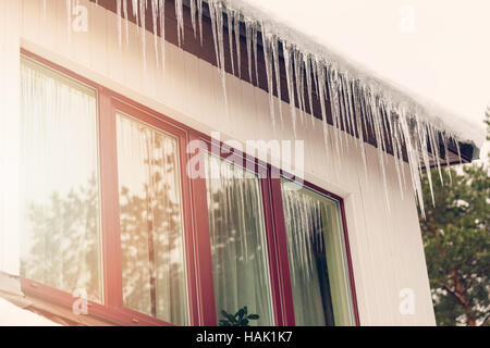 Wärmeverlust - Eiszapfen hängen auf Hausdach Stockfoto