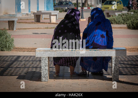 Entspannen Sie auf einer Bank an einem heißen Sommertag. Zwei arabische bekränzt Frauen reden beim Sitzen auf einer Bank. Stockfoto