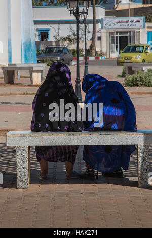 Entspannen Sie auf einer Bank an einem heißen Sommertag. Zwei arabische bekränzt Frauen reden beim Sitzen auf einer Bank. Stockfoto