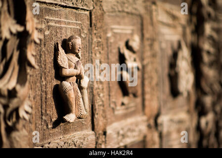 MANDALAY Myanmar // MANDALAY, Myanmar — aufwändig geschnitzte Figuren zieren die Türverkleidungen des Shwenandaw Klosters (auch bekannt als Shwe Nandaw Kyaung), der einzigen erhaltenen ursprünglichen Holzkonstruktion aus dem Mandalay Royal Palace Komplex. Das 1878 aus Teakholz erbaute Kloster war ursprünglich König Mindon Mindon Minds private königliche Wohnung, wo er 1878 starb. König Thibaw Min baute das Gebäude innerhalb von Tagen nach dem Tod seines Vaters in ein buddhistisches Kloster um und verlegte es an seinen heutigen Standort in der Nähe des Mandalay Hill. Das Kloster Stockfoto