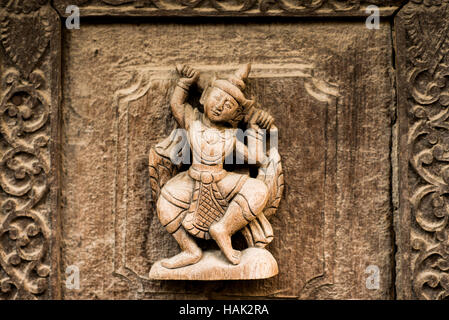 MANDALAY Myanmar // MANDALAY, Myanmar — Tanzfiguren aus Teakholz im Shwenandaw Kloster (auch bekannt als Shwe Nandaw Kyaung), dem einzigen noch erhaltenen ursprünglichen Holzbau aus dem Mandalay Royal Palace Komplex. Das 1878 erbaute Kloster war ursprünglich König Mindon Mindons private königliche Wohnung, in der er starb, und wurde dann von König Thibaw Min innerhalb von Tagen nach dem Tod seines Vaters in ein buddhistisches Kloster umgewandelt. Das Gebäude wurde 1857 von Elefanten aus dem Amarapura-Palast entfernt, als die Hauptstadt nach Mandalay zog. Konstruiert Stockfoto