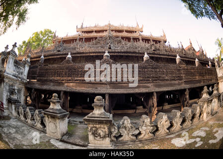 Shwenandaw Kloster Teakholzschnitzereien Mandalay Myanmar // MANDALAY, Myanmar – das Äußere des Shwenandaw Klosters (auch bekannt als Shwe Nandaw Kyaung) zeigt komplexe Teakholzschnitzereien, die buddhistische Mythologie und Jataka-Geschichten darstellen. Das 1878 erbaute Kloster war ursprünglich König Mindon Mindons private königliche Wohnung im Mandalay Palace Komplex, bevor es nach dem Tod des Königs in ein buddhistisches Kloster umgewandelt wurde. Das Gebäude stellt das einzige erhaltene ursprüngliche Holzgebäude aus dem königlichen Palast dar und wurde vollständig aus Teakholz mit traditionellen Einsteckstutzen und Tenon Joi gebaut Stockfoto