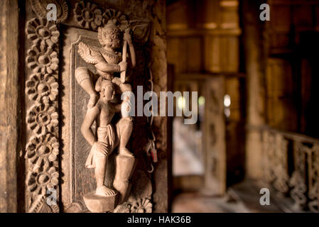 Shwenandaw Kloster Holzschnitzereien Mandalay Myanmar // MANDALAY, Myanmar — komplizierte Holzschnitzereien mit Figuren aus buddhistischer Ikonographie zieren eine Tür im Shwenandaw Kloster (auch bekannt als Shwe Nandaw Kyaung). Das 1878 aus geschnitztem Teakholz erbaute Kloster war ursprünglich König Mindon Mindons private königliche Wohnung, in der er 1878 starb und dann von seinem Sohn König Thibaw Min in ein buddhistisches Kloster umgewandelt wurde. Das Gebäude war ursprünglich Teil des Amarapura-Palastes, bevor es 1857 von Elefanten als Teil der neuen königlichen Hauptstadt nach Mandalay transportiert wurde. Das Shwenandaw-Kloster ist das Stockfoto