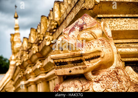 Shwezigon Pagoda Guardian Lion Sculpture Nyaung-U Myanmar // NYAUNG-U, Myanmar — Eine Wächter-Löwe-Skulptur, die sich an einer der Ecken der Basis der Hauptstupa in der Shwezigon Pagoda (auch bekannt als Shwezigon Paya) befindet. Die Pagode, die im 11. Jahrhundert während der Regierungszeit von König Anawrahta erbaut wurde, ist eines der wichtigsten buddhistischen Denkmäler Myanmars und ein Prototyp für spätere burmesische Stupas. Schutzlöwen, die lokal als Chinthe bekannt sind, dienen traditionell als Schutzfiguren in der burmesischen buddhistischen Architektur. Die Shwezigon-Pagode befindet sich in Nyaung-U, in der Nähe der antiken Stadt Bagan in Myanmar. Stockfoto