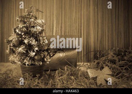 kleinen künstlichen Weihnachtsbaum mit Spielzeugen und Bögen auf hölzernen Hintergrund für Postkarten und Grüße zu Weihnachten und Neujahr Stockfoto