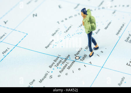 Nahaufnahme von Miniatur Figur des jungen Reisenden steht auf große Karte neben Tahiti Inseln Stockfoto