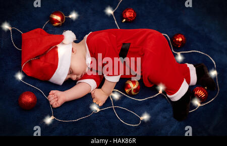 Aufwand für Baby schläft in Santa Outfit mit Lichterketten Stockfoto