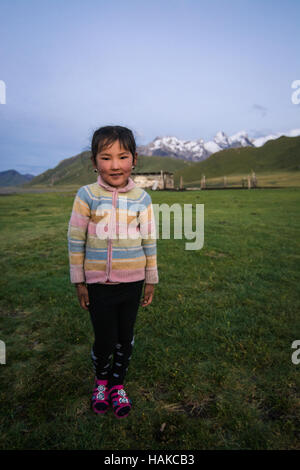 Glückliche kleine Mädchen im Hinterhof ihrer Familie Jurte Zelt auf 3000 m Seehöhe, nahe Grenze zu China, Kirgisistan Stockfoto