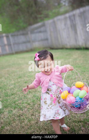 Kleinkind Mädchen laufen und lächelnd mit vollen Osterei Bakset Stockfoto