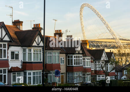 Der Bogen des Wembley-Stadion gesehen über den Dächern von s-Bahn beherbergt Wembley, London. Stockfoto