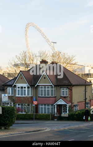 Der Bogen des Wembley-Stadion gesehen über den Dächern von s-Bahn beherbergt Wembley, London. Stockfoto