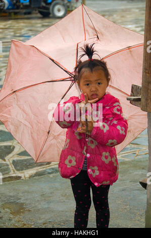 Ein kleines Kind im Kam-Dong-Dorf geht mit Schirm im Regen. Stockfoto