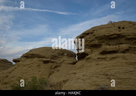 Die Felsformationen aus Sandstein aus einem Winkel mit blauem Himmel und dünn, Cirruswolken über und Vegetation im Vordergrund fotografiert. Stockfoto