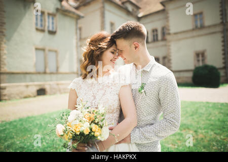 Glückliche Hochzeit paar umarmt und lächelnd einander auf Hintergrund altes Schloss Stockfoto