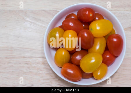 Rote und gelbe Cherry-Tomaten in eine Schüssel geben. Stockfoto