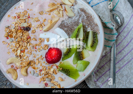 Bananen-Erdbeer Smoothie mit Kiwi, Chia, Müsli mit Nüssen und Kokos in eine Schüssel geben. Perfekt für die Detox-Diät oder einfach nur eine gesunde Mahlzeit.  Liebe für ein hea Stockfoto