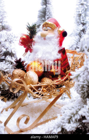 Santa Claus Figur sitzt auf einem goldenen Schlitten in einem verschneiten Wald Stockfoto