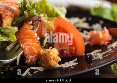 Konzept: Speisekarten, gesundes Essen, hausgemachte, Feinschmecker, Völlerei. Caesar Salat mit Lachs und Cherry Tomaten auf einem verwitterten hölzernen Zeitmessung Stockfoto