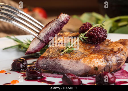 Konzept: Speisekarten, gesundes Essen, hausgemachte, Feinschmecker, Völlerei. Geschnittene Stücke Schweinefleisch Steak auf den Knochen mit Kirsch-Ingwer-Sauce mit ingred Stockfoto