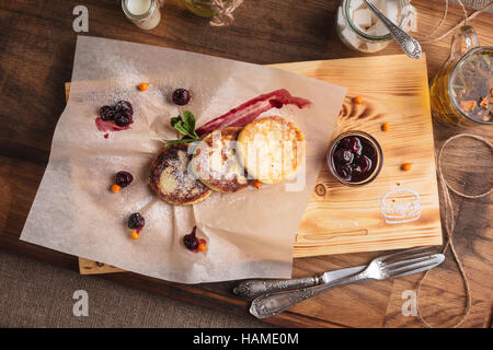 Konzept: Speisekarten, gesundes Essen, hausgemachte, Feinschmecker, Völlerei. Käse-Pfannkuchen mit Kirschsauce mit Zutaten auf Vintage auf Papier serviert. Stockfoto