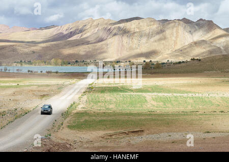 Ein Offroad-Fahrzeug bewegt sich entlang einer unbefestigten Straße hinter Tislit See und die Berge des marokkanischen atlas Stockfoto