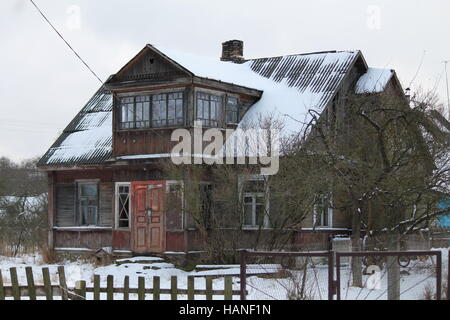 alte Mode Holzhaus mit Veranda und Geländer mit großen Garten Aufenthalt bedeckt Schnee Stockfoto