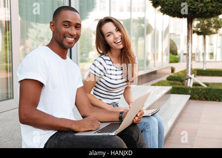 Fröhliche multiethnischen junges Paar mit Laptop und Lachen im freien Stockfoto