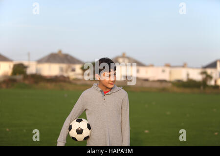 Junge mit Fußball außerhalb der goldenen Stunde bei Sonnenuntergang Stockfoto