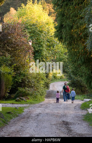 Vater und Kinder gehen einer bewaldeten englischen Country-Gasse im Herbst, Grindleford, Peak District, Derbyshire, UK Stockfoto