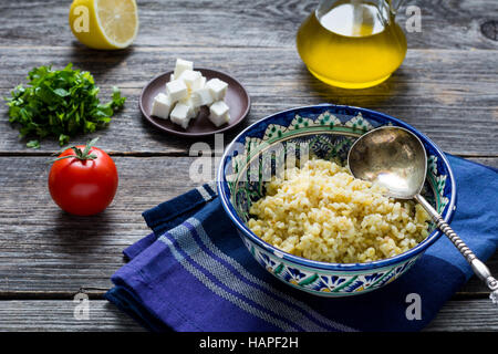 Zutaten für das Kochen Taboulé Salat mit Bulgur, Tomaten, Petersilie, Zitrone, Olivenöl und frischem Ziegenkäse Käse auf hölzernen Tisch bac Stockfoto