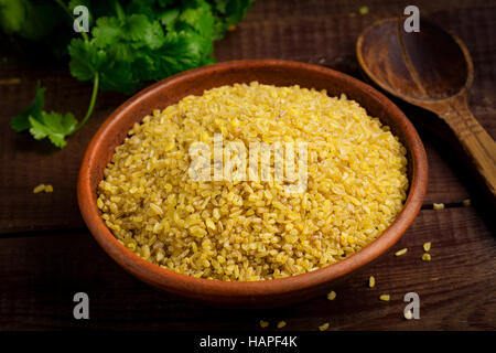 Rohe Bulgur, Weizenkörner in Schüssel auf Holztisch. Nahaufnahme Stockfoto