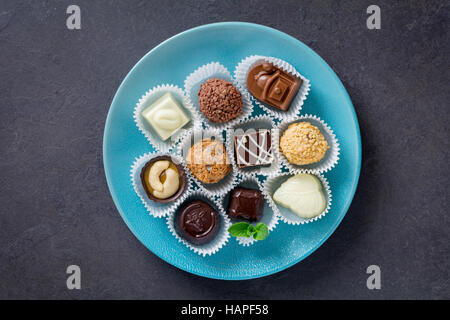 Auswahl an feinen Pralinen auf der blauen Platte. Ansicht von oben Stockfoto