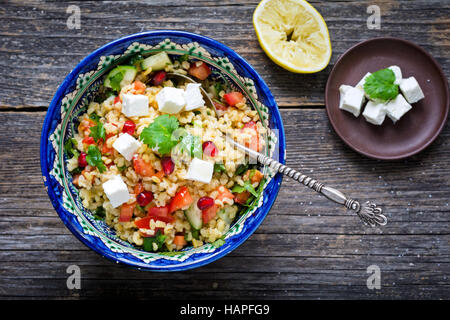 Schüssel mit gesunden und leckeren frischen Taboulé Salat mit Bulgur, Granatapfel und Fetakäse Stockfoto