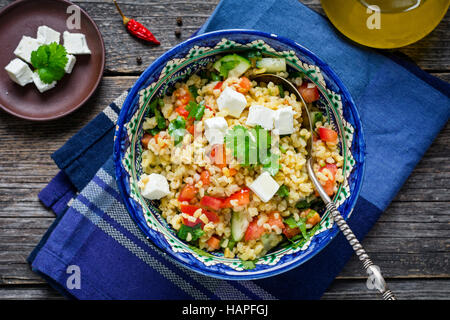 Schüssel mit gesunden und leckeren frischen Taboulé Salat mit Bulgur, Granatapfel und Fetakäse Stockfoto