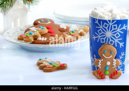 Niedliche kleine Lebkuchenmänner mit Schneeflocke Tasse heiße Schokolade verziert und Mini Marshmallows für Weihnachten zu behandeln Stockfoto