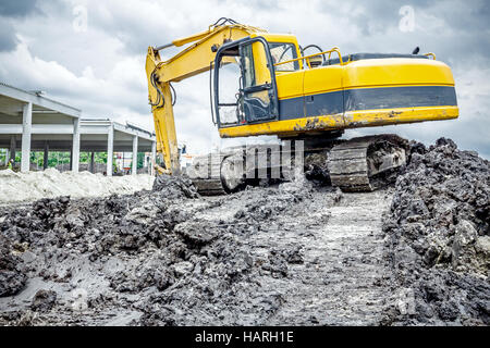 Gelbe Bagger macht Flor des Bodens durch Hochziehen Boden auf Heap auf Baustelle, Projekt im Gange. Stockfoto