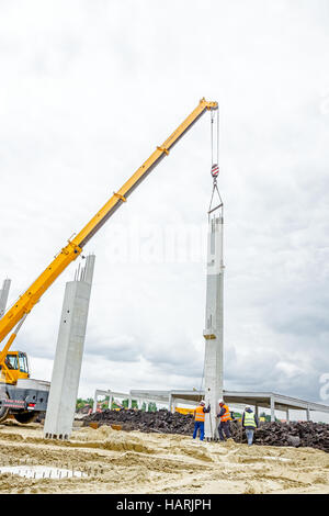 Mobiler Kran ist zur Montage Betonpfeiler auf neue Gebäude, Menschen arbeiten. Stockfoto