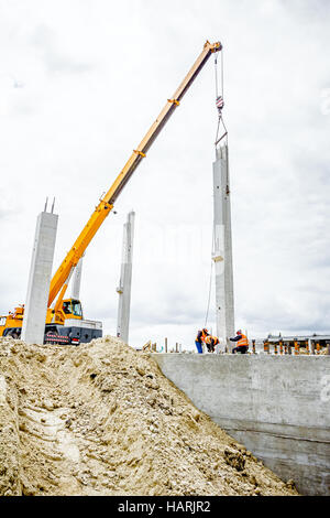 Mobiler Kran ist zur Montage Betonpfeiler auf neue Gebäude, Menschen arbeiten. Stockfoto