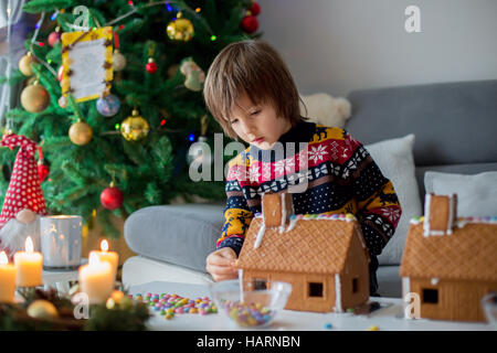 Entzückende Vorschulkind beherbergt junge, Lebkuchen dekorieren für Weihnachten zu Hause Weihnachtsbaum hinter ihnen, Advent Kerzen auf dem Tisch Stockfoto