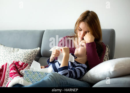 Junge Mutter mit ihrem kleinen kranken Jungen, zusammen auf der Couch liegen Stockfoto