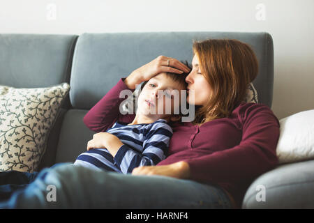 Junge Mutter mit ihrem kleinen kranken Jungen, zusammen auf der Couch liegen Stockfoto