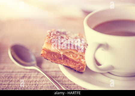 Kaffeepause, Vintage-Stil Foto einer Kaffeetasse mit kleinen leckeren Stück Kuchen, köstliches Dessert im Café Stockfoto