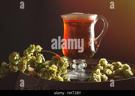 Bier in einer antiken geätztem Glas Krug sitzen auf Lauf mit Hopfen Stockfoto