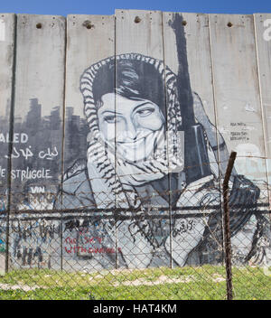 BETHLEHEM, ISRAEL - 6. März 2015: Detail des Graffiti auf der Sperrmauer. Palästinenserin mit der Waffe. Stockfoto