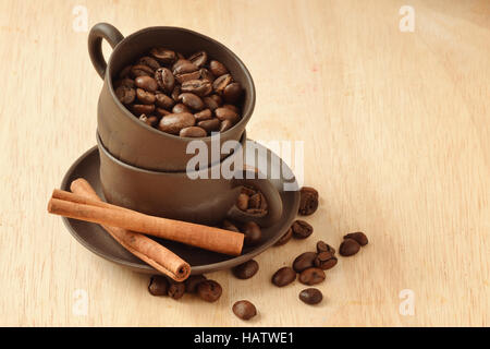 Kaffeebohnen in eine Tasse und Zimt-Sticks auf hölzernen Hintergrund Stockfoto
