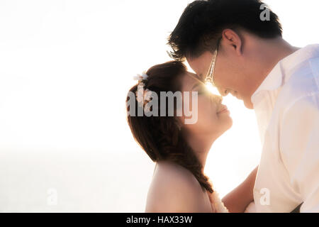 Asiatische romantisch heiratete paar küssen mit dem Sonnenuntergang im Hintergrund. Braut und Bräutigam. Stockfoto