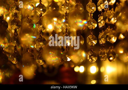 Orangefarbene Pendelleuchte mit kleinen Glasdiamanten auf dunkel verschwommenem Hintergrund Stockfoto