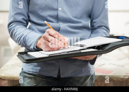 Mann, der Hinweise auf Notebook im Büro schreibt Stockfoto