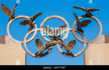 Olympische Ringe mit Tauben über die Bronze-Skulptur von Pierre de Coubertin, Vater der modernen Olympischen Spiele, in Atlanta, Georgia. Stockfoto