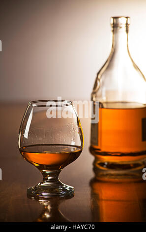 Cognac im Glas mit Flasche auf Holztisch Stockfoto
